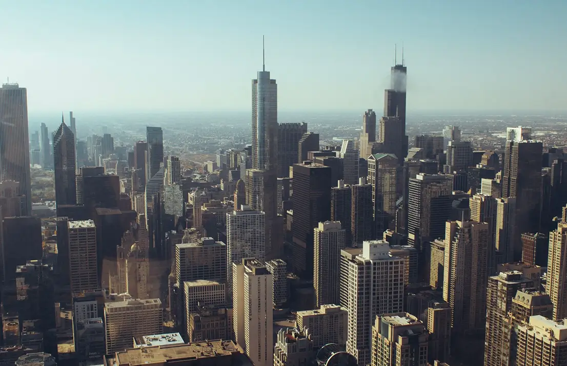 Aerial view of a city skyline with numerous skyscrapers under a clear sky during daytime.