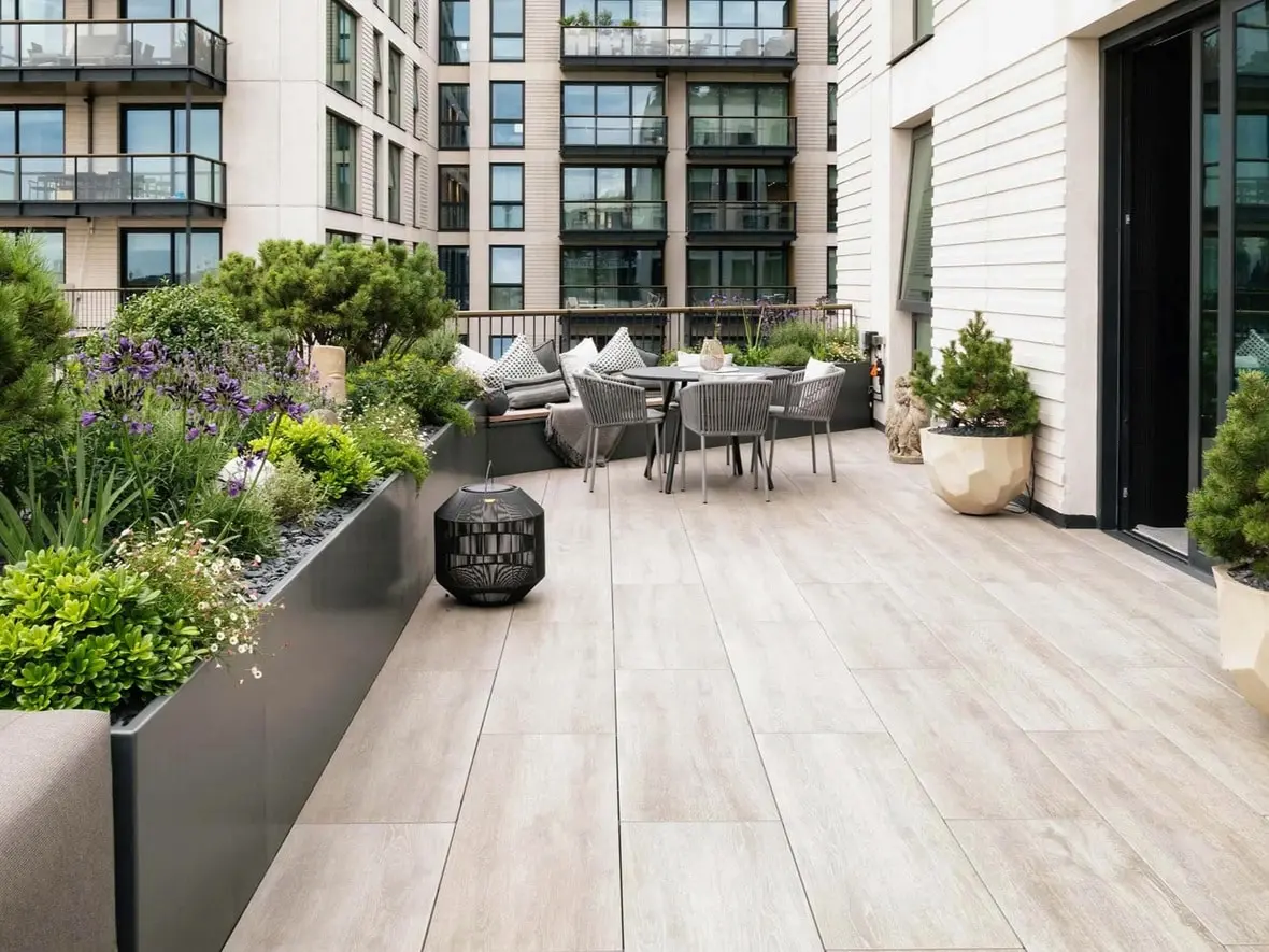 Stylish NYC rooftop terrace with porcelain pavers, lush planters, and outdoor dining area