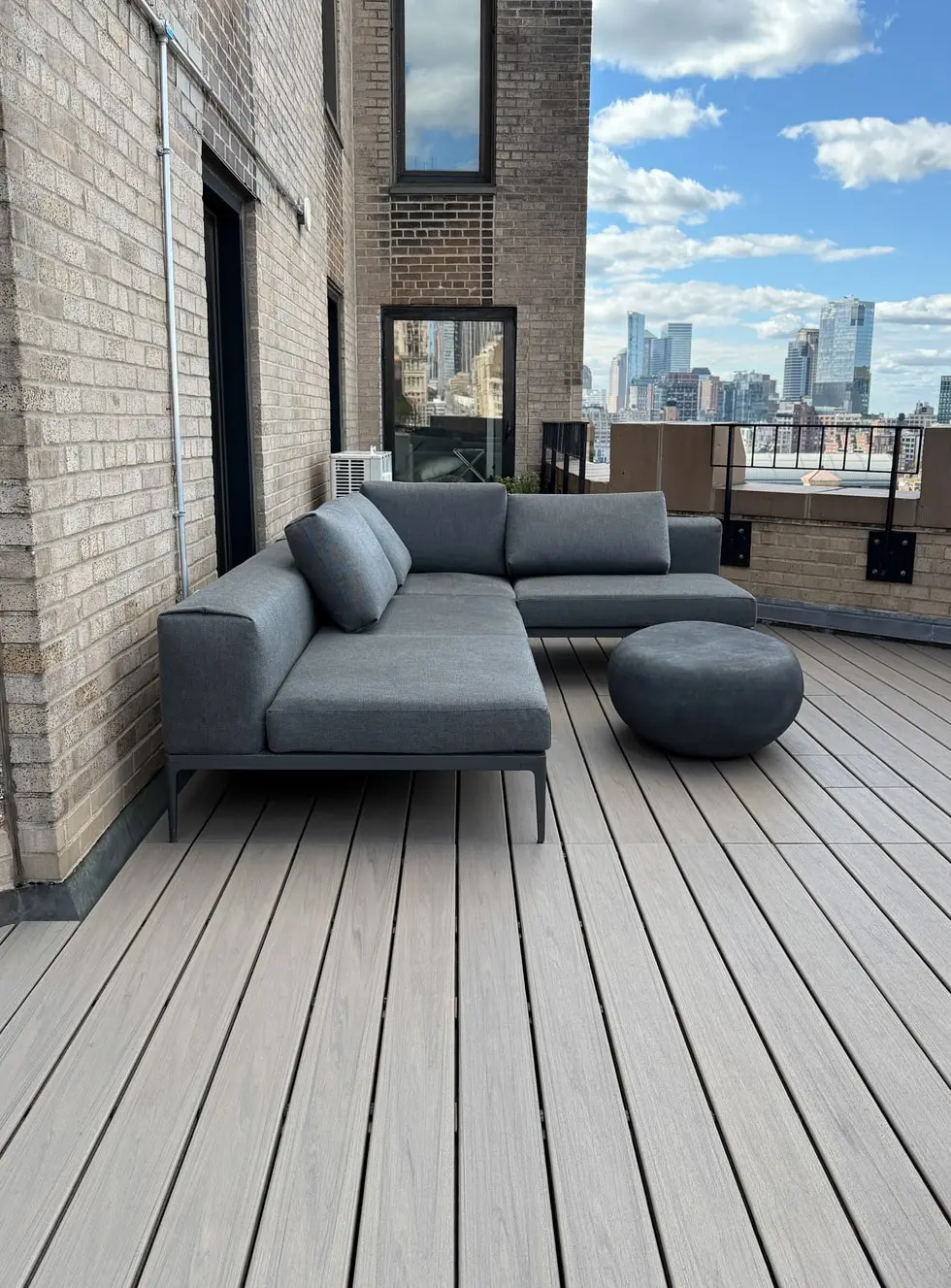 Rooftop deck in NYC with gray composite decking and modern outdoor sectional sofa