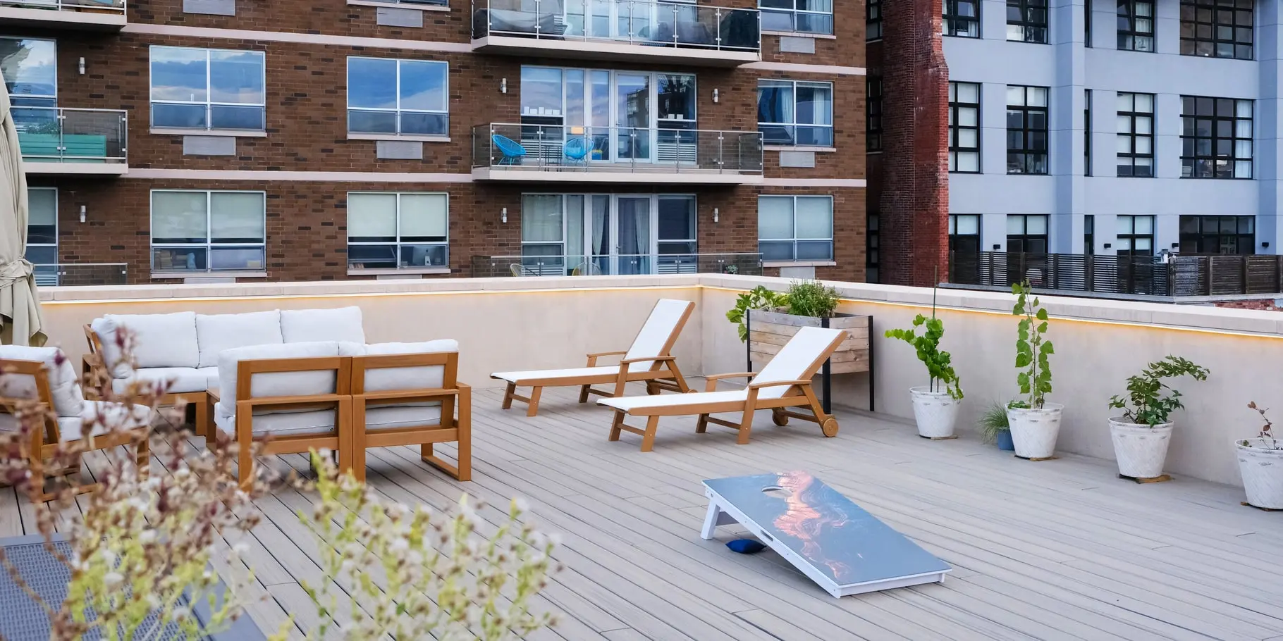 Modern rooftop terrace in Long Island City featuring Trex decking, lounge seating, planters, and perimeter LED lighting.