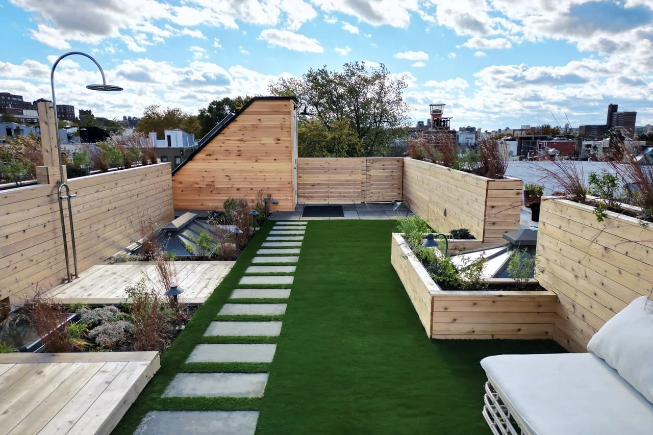 Brooklyn rooftop deck with custom wood privacy walls, built-in planters, artificial turf, and integrated lighting, constructed by a roof deck contractor in NYC.