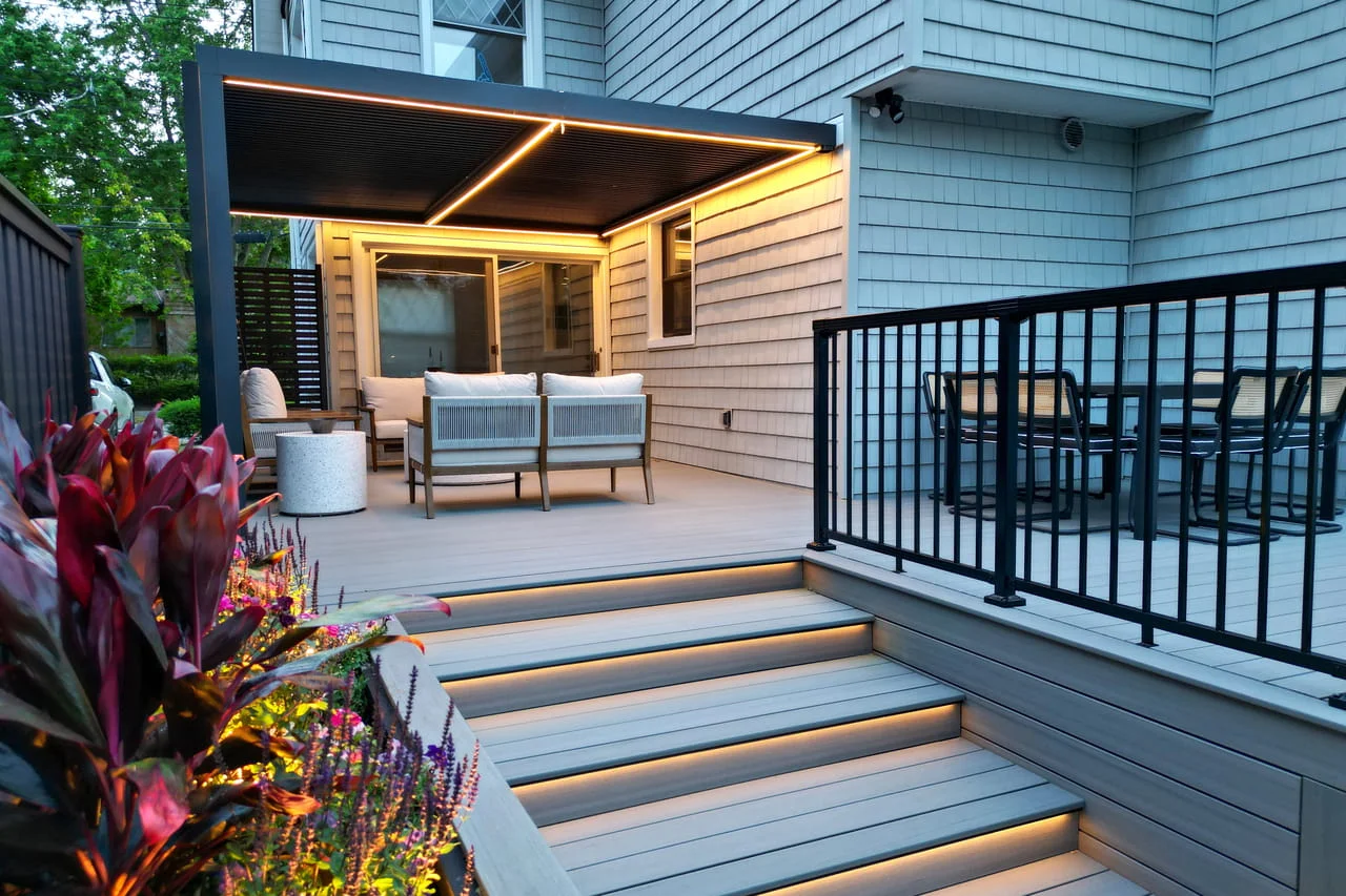 Brooklyn backyard composite deck with aluminum pergola, integrated LED stair lighting, and black aluminum railing, built by a professional deck contractor.