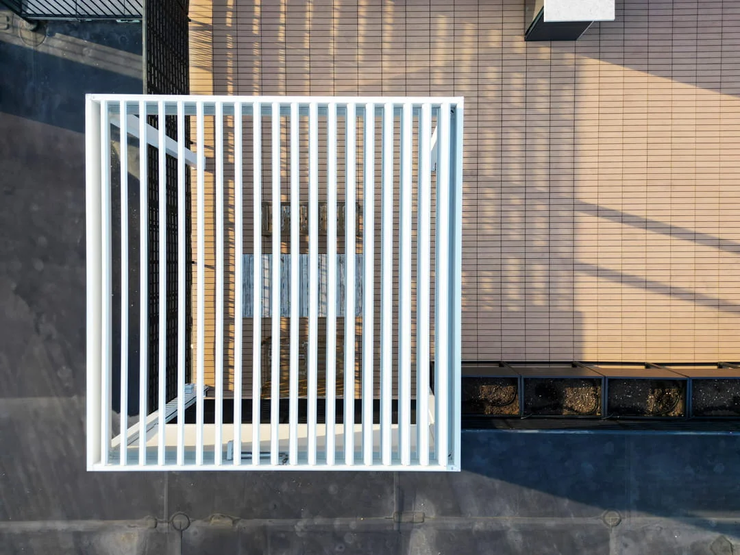 White aluminum louvered pergola by PERGOLUX on an NYC rooftop with tile cladding and roof membrane visible