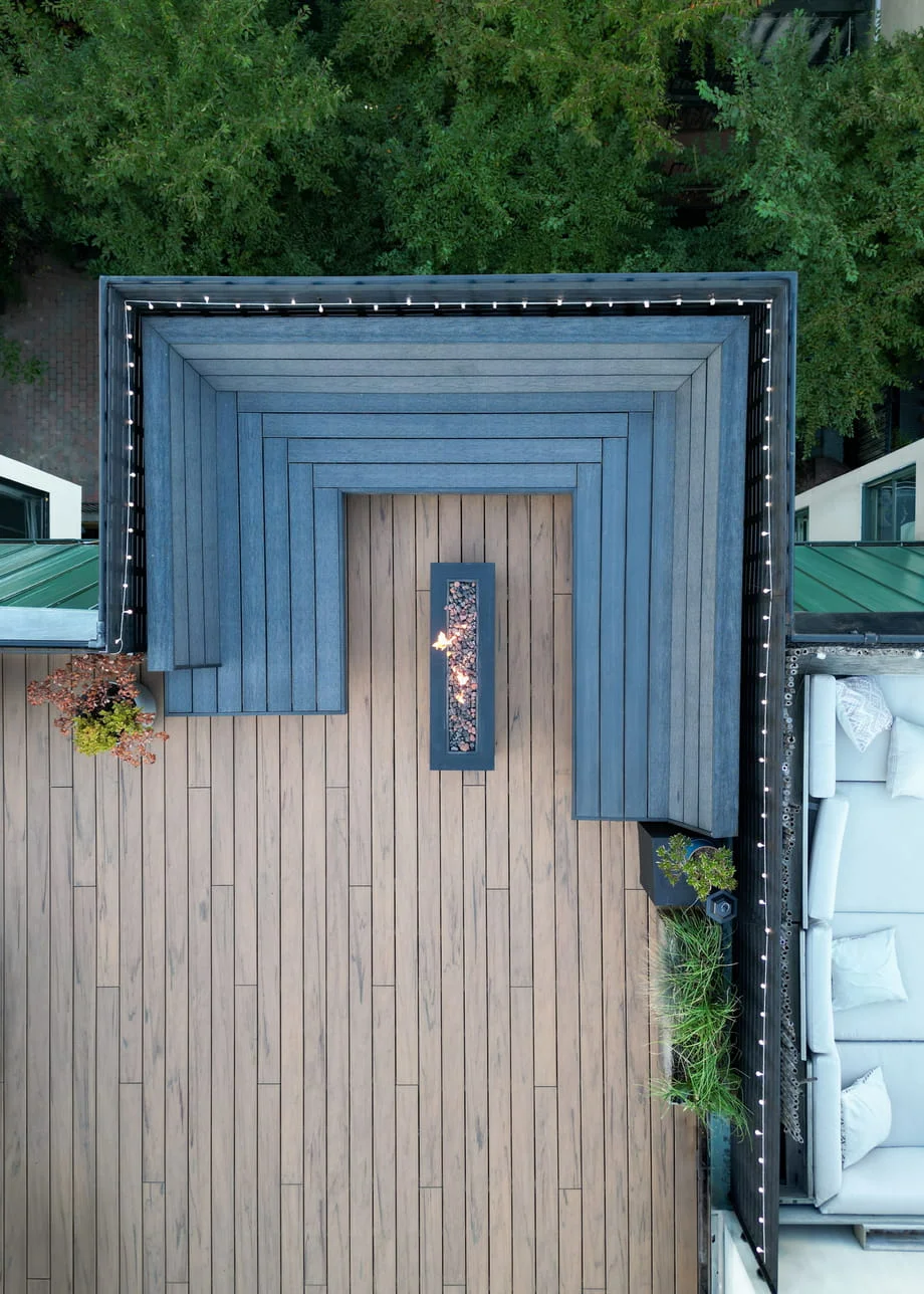 Composite rooftop deck from above with a wraparound bench, string lights, and an outdoor sofa in New York