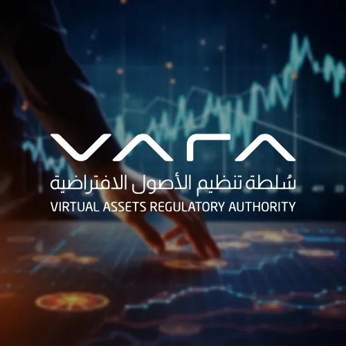 A close-up of a hand interacting with a digital screen that displays fluctuating financial graphs. The VARA logo is centered, with text in both English and Arabic reading "Virtual Assets Regulatory Authority."
