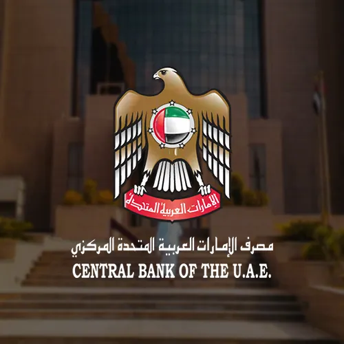 The Central Bank's emblem, featuring a golden eagle holding a red banner with Arabic text, positioned in front of the main entrance of the Central Bank building.
