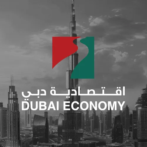 The Dubai Economy logo, with a green and red emblem in the shape of the UAE flag, overlaying a black-and-white image of the Dubai skyline.