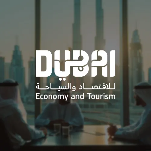 A logo with the word "Dubai" in bold, representing Dubai Economy and Tourism. The text is written in both English and Arabic, with a background showing a group of businesspeople in a meeting, and the Burj Khalifa visible through the window.