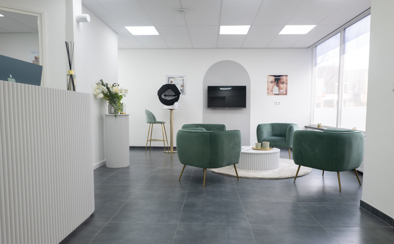 The waiting area inside Ella Clinics, featuring modern green armchairs, a white reception desk, and minimalist decor.