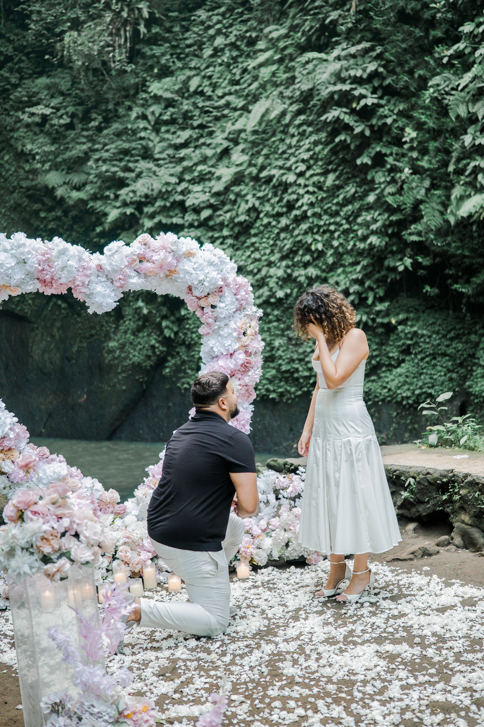 Groom dropping to one knee for a surprise helicopter proposal on a private Bali cliffside.