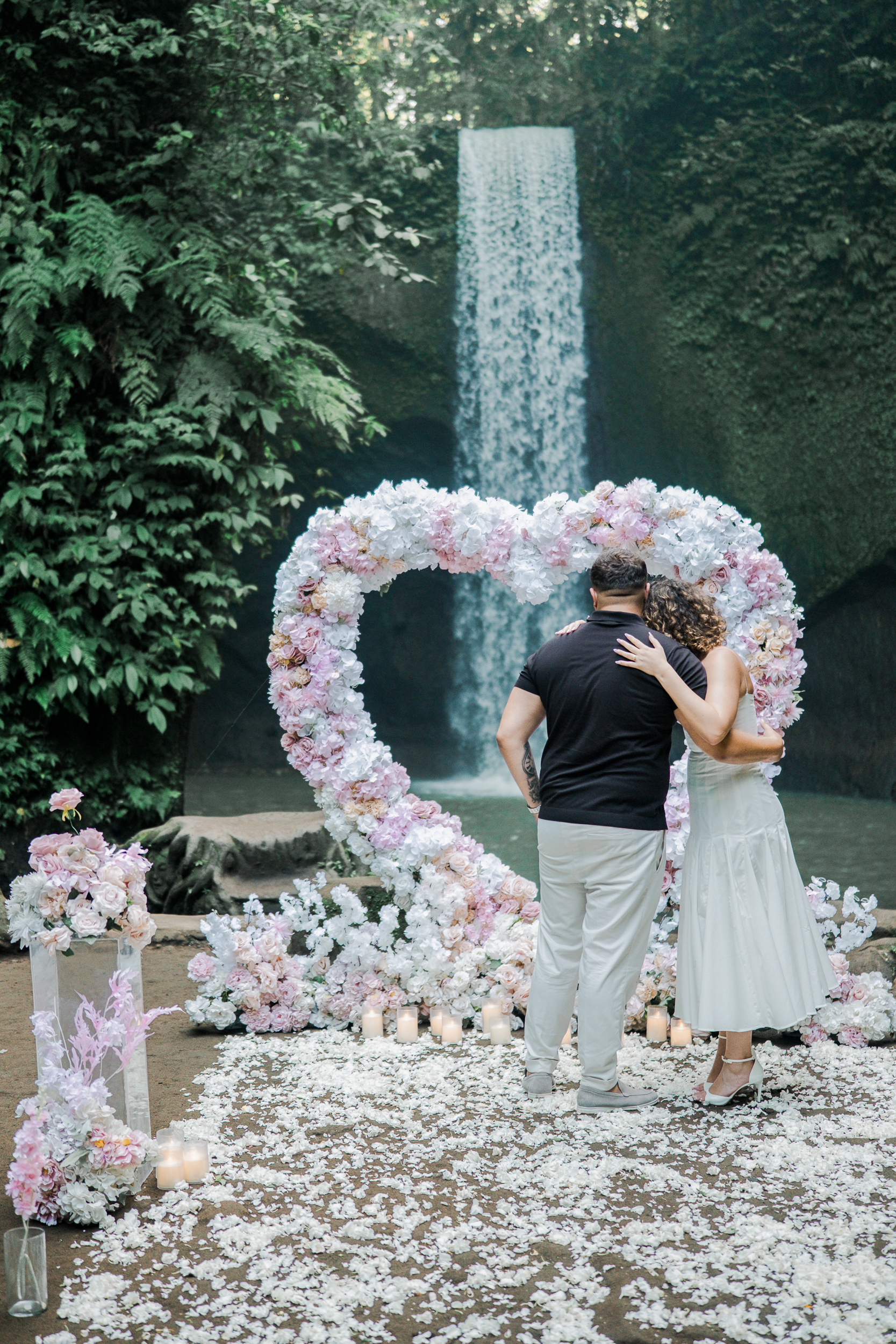 ewly engaged couple smiling and showing off the diamond engagement ring after a Bali cliffside proposal.