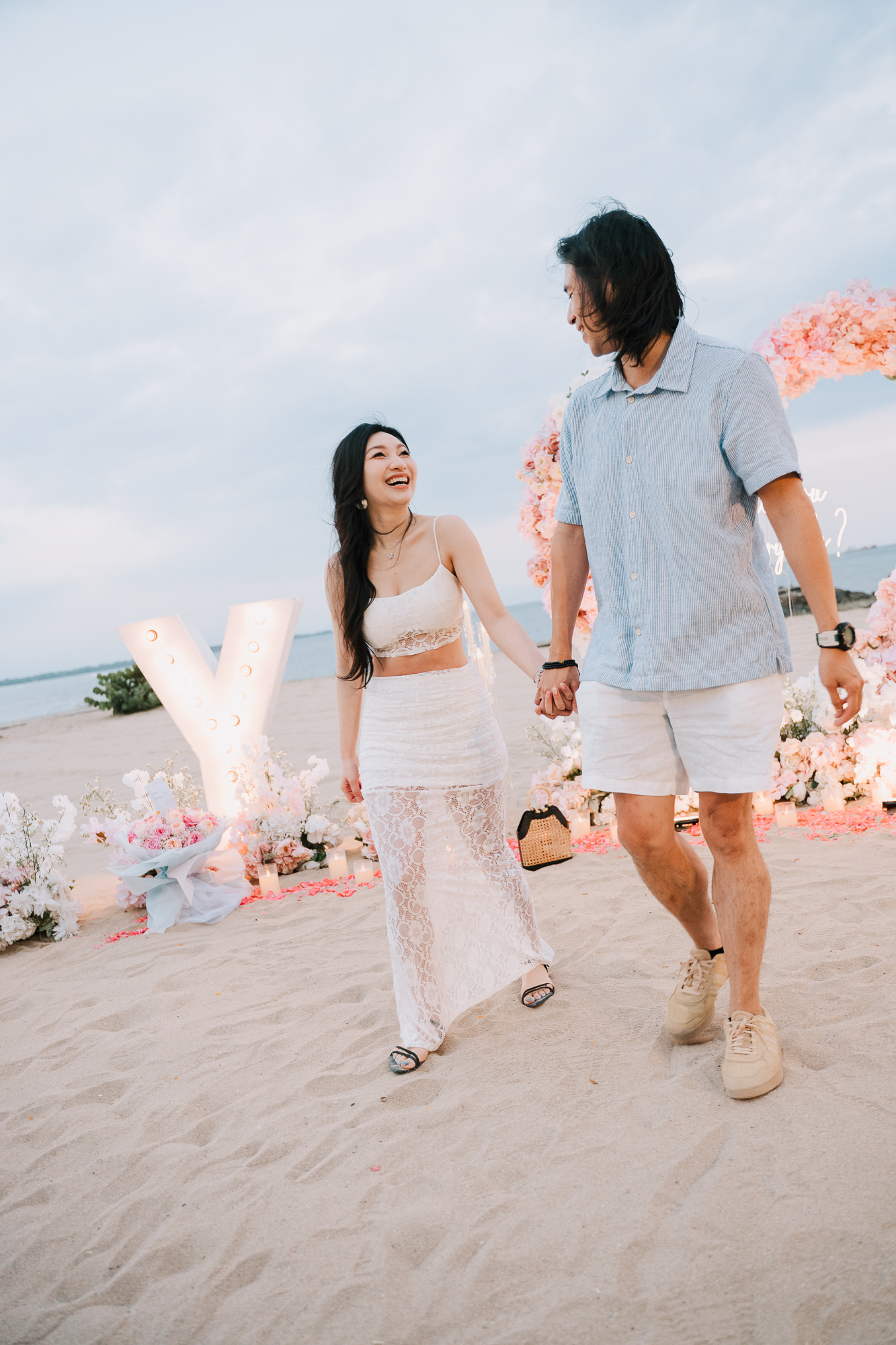 Newly engaged couple walking along the shore together smiling after saying yes