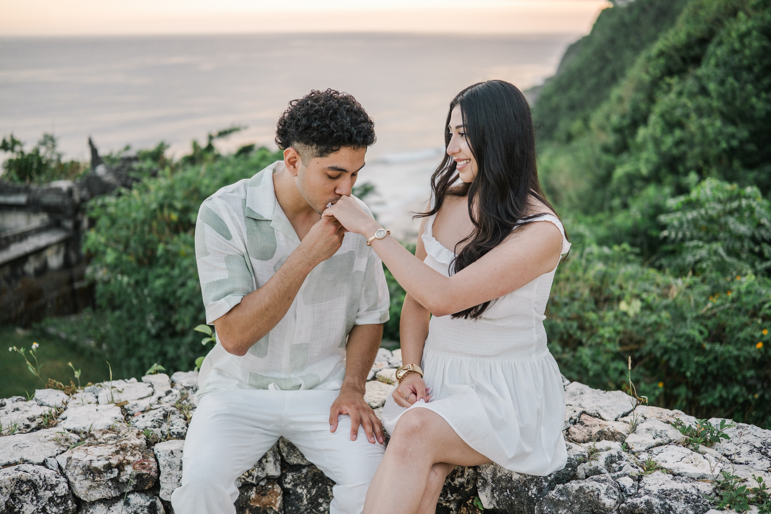 Romantic moment on a stone cliff ledge overlooking the ocean in Uluwatu