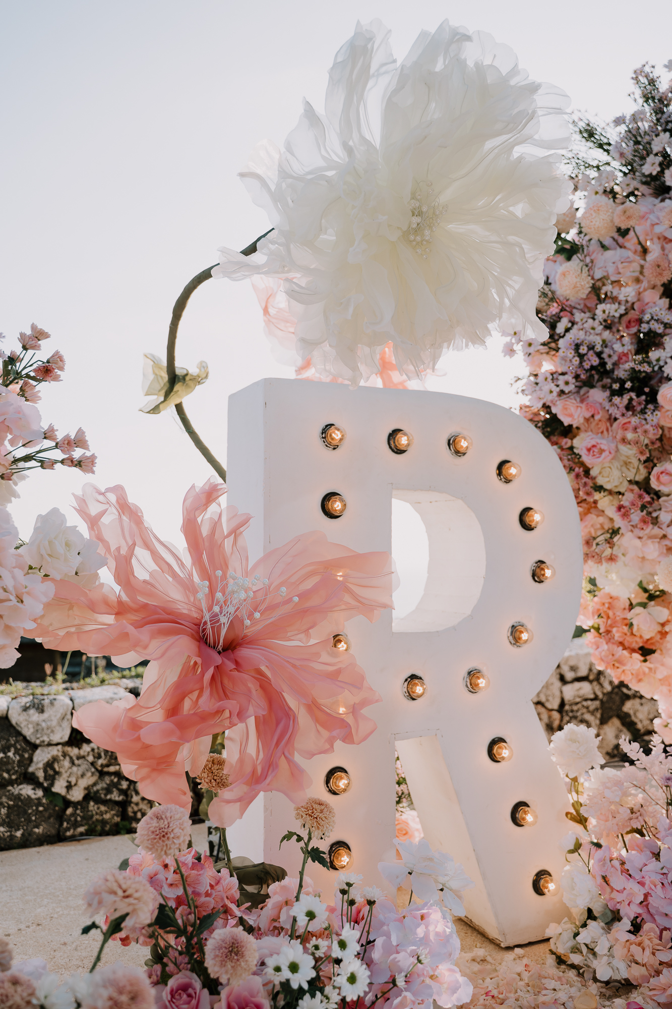 Close-up detail of an illuminated initial marquee letter R with blush floral styling