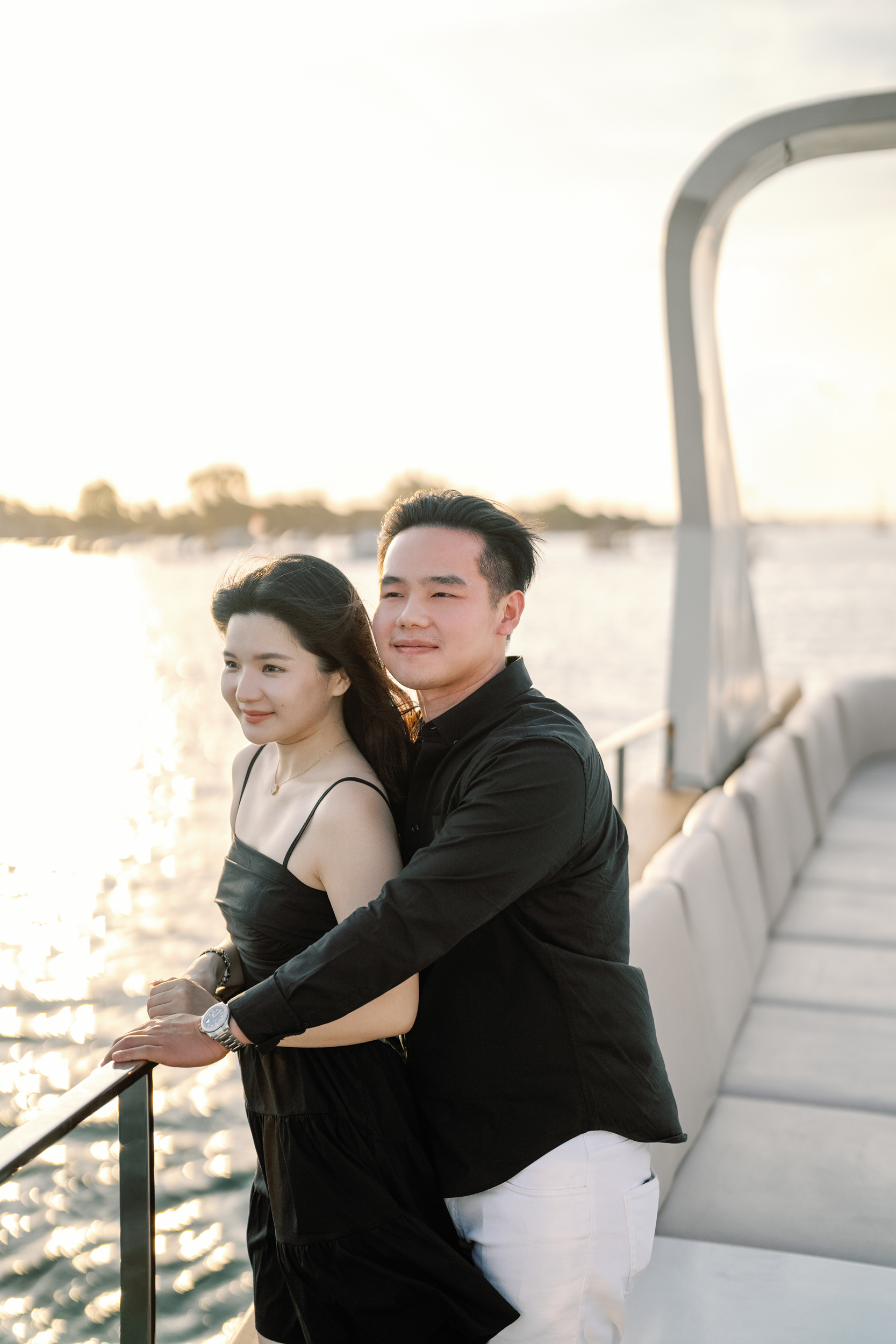 Couple embracing on the deck of a private yacht at sunset during a luxury Bali surprise proposal.