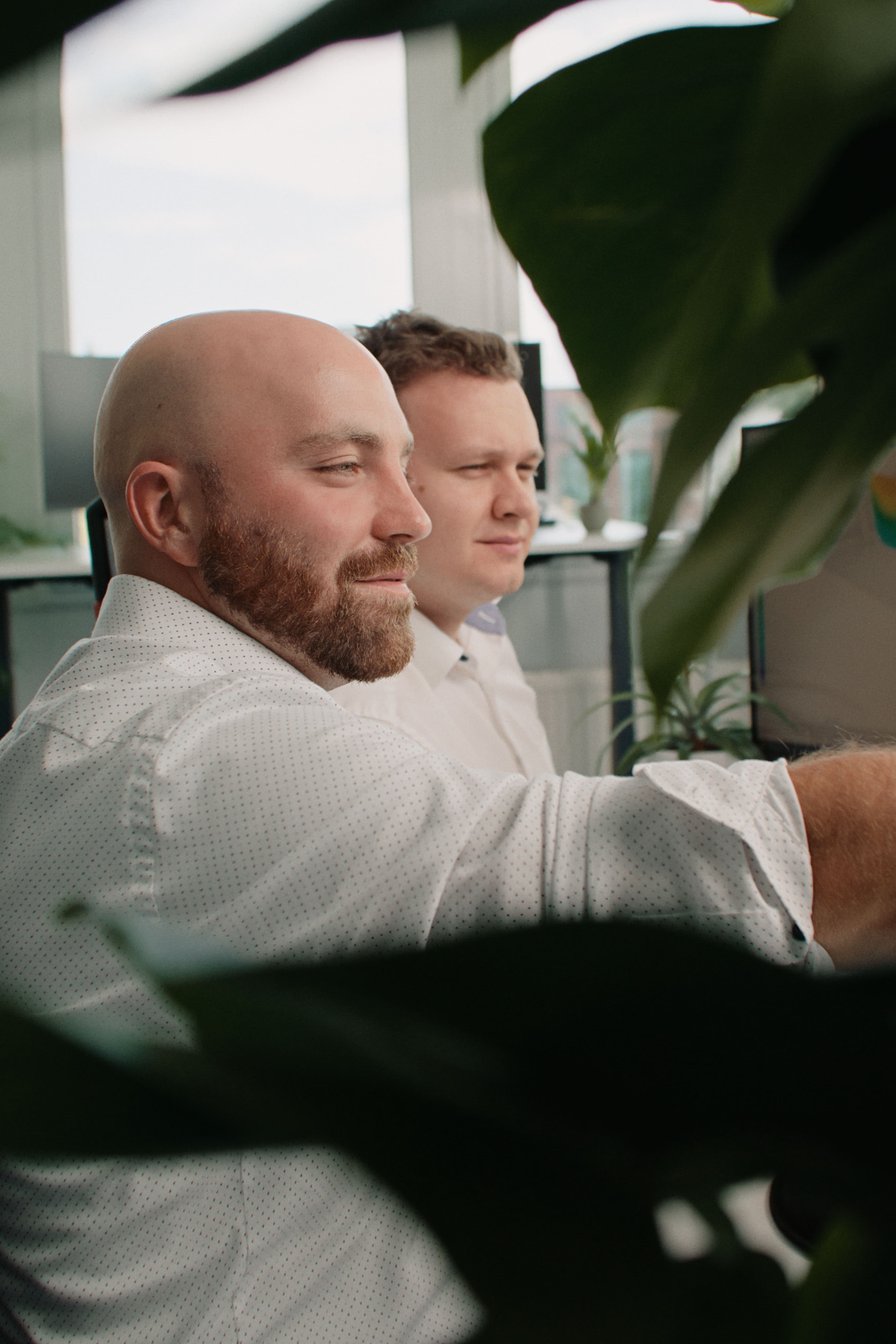 Zwei motivierte Mitarbeiter der Reving GmbH blicken konzentriert auf einen Bildschirm im Büro.