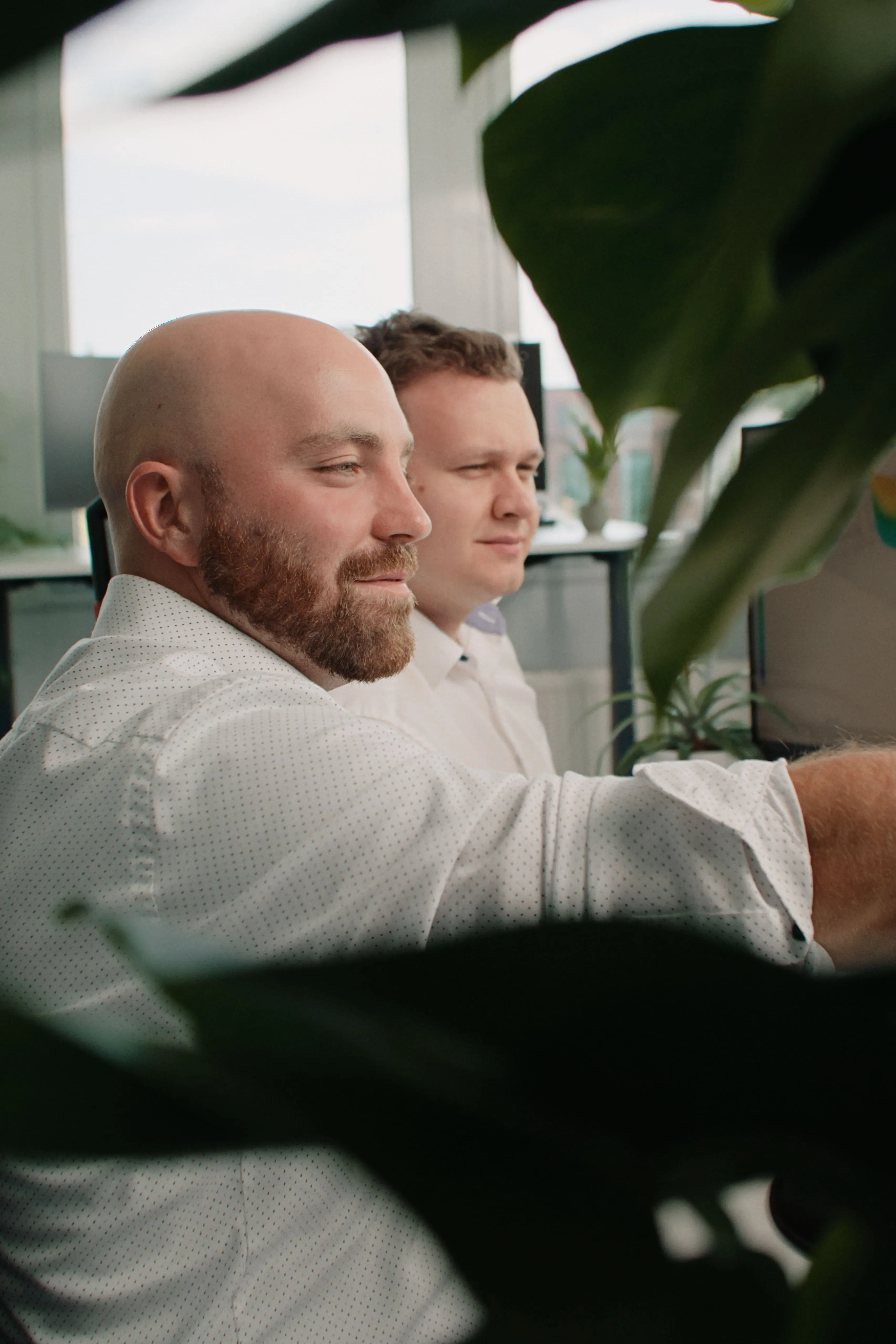 Zwei motivierte Mitarbeiter der Reving GmbH blicken konzentriert auf einen Bildschirm im Büro.