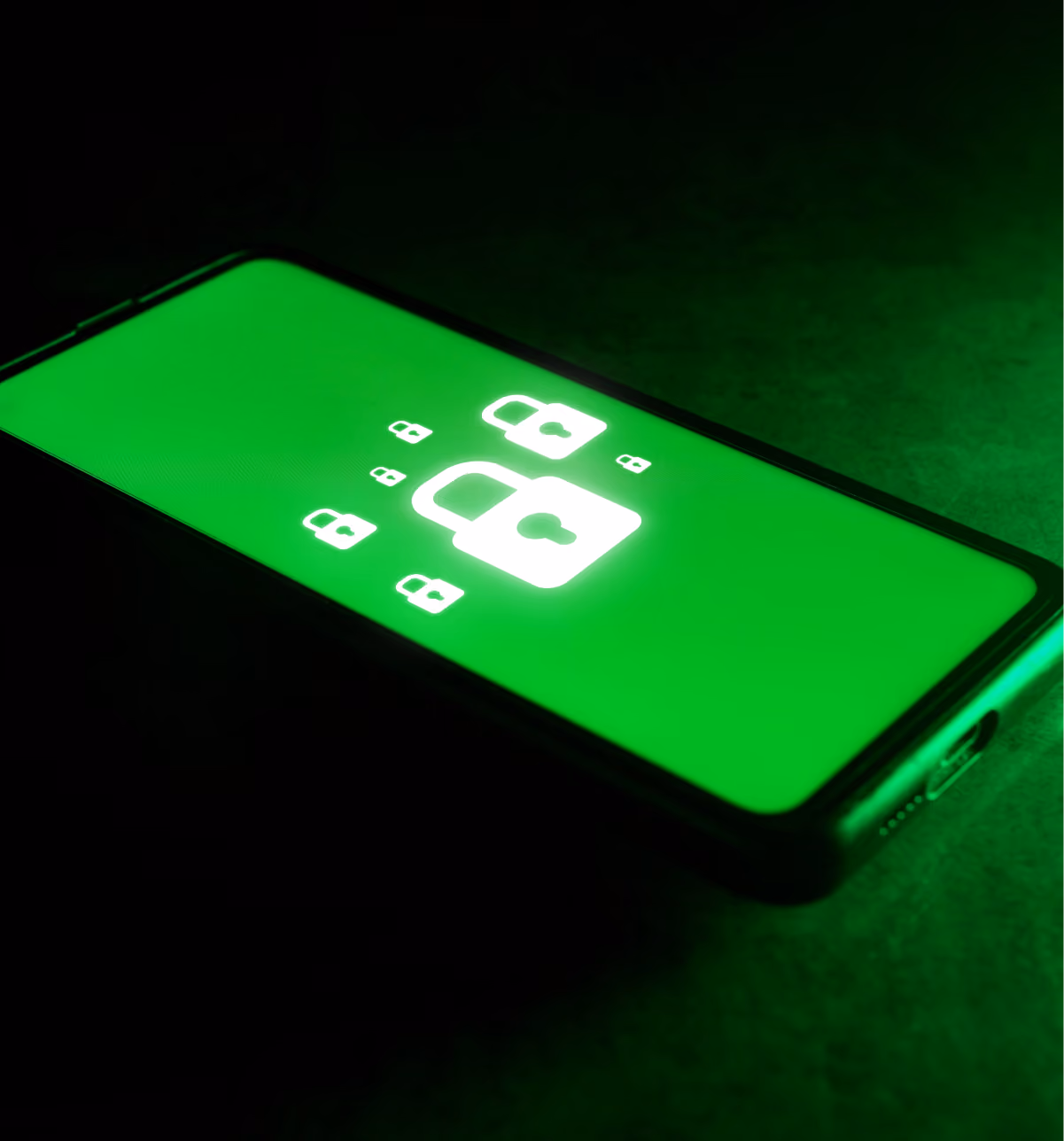 Smartphone placed on a dark surface displaying a green screen with multiple glowing white padlock icons, symbolizing security or privacy.