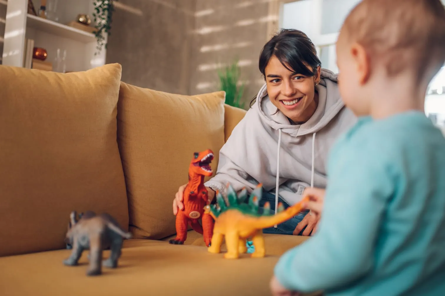 woman plays dinosaurs with child and smiles 