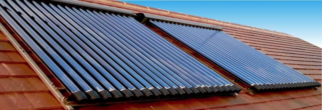 Eine Solarthermie Anlage auf einem roten Dach mit blauem Himmel im Hintergrund