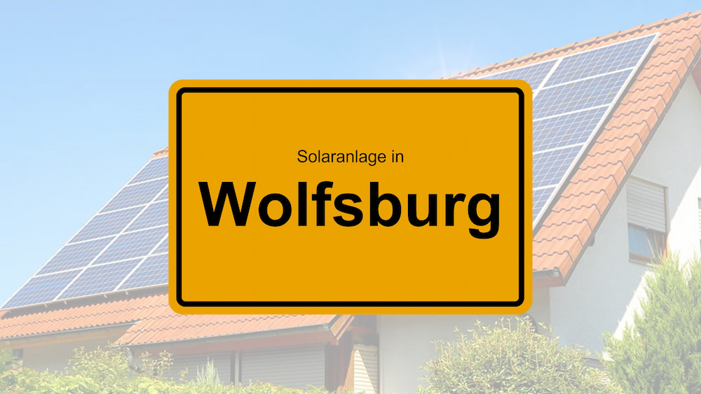 Ortsschild Wolfsburg mit Solarhaus im Hintergrund