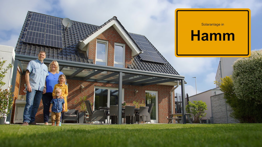 Familie vor Haus mit Solaranlage und Ortsschild Hamm
