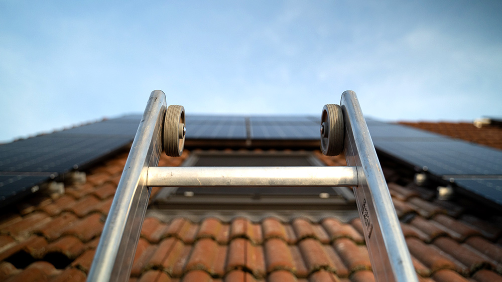 Hausdach mit Solaranlage und Leiter im Vordergrund