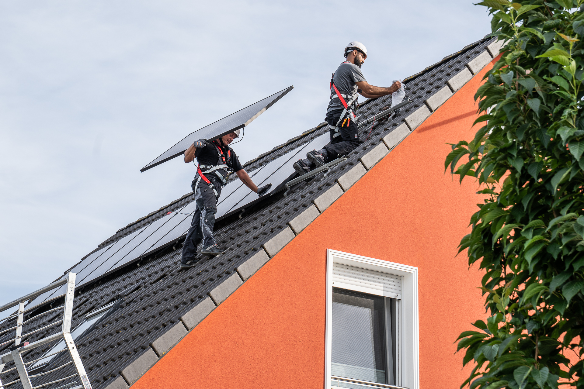 Zwei Solarmonteure auf einem Dach. Sie installieren Solarmodule.