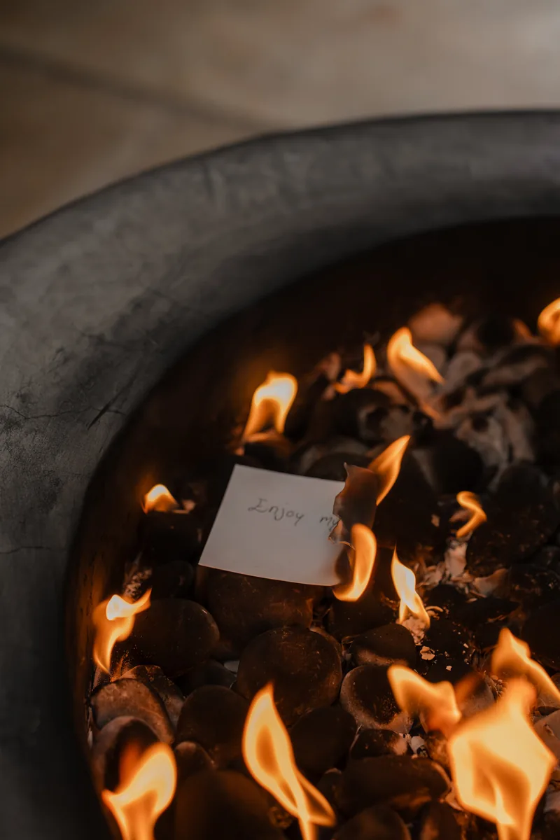 A handwritten note catching fire in a stone fire pit