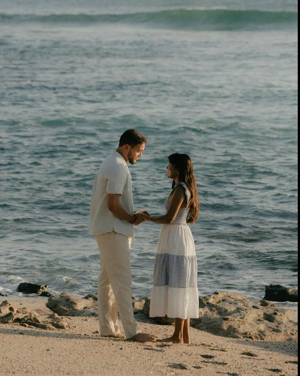 Couple holding hands barefoot on a rocky Guanacaste beach with Pacific waves behind them during a surprise proposal photoshoot in Costa Rica