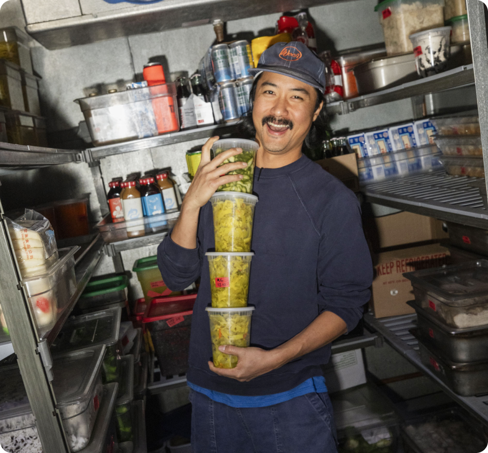 Homebase restaurant scheduling customer grabbing a stack of ingredients from walk-in fridge.