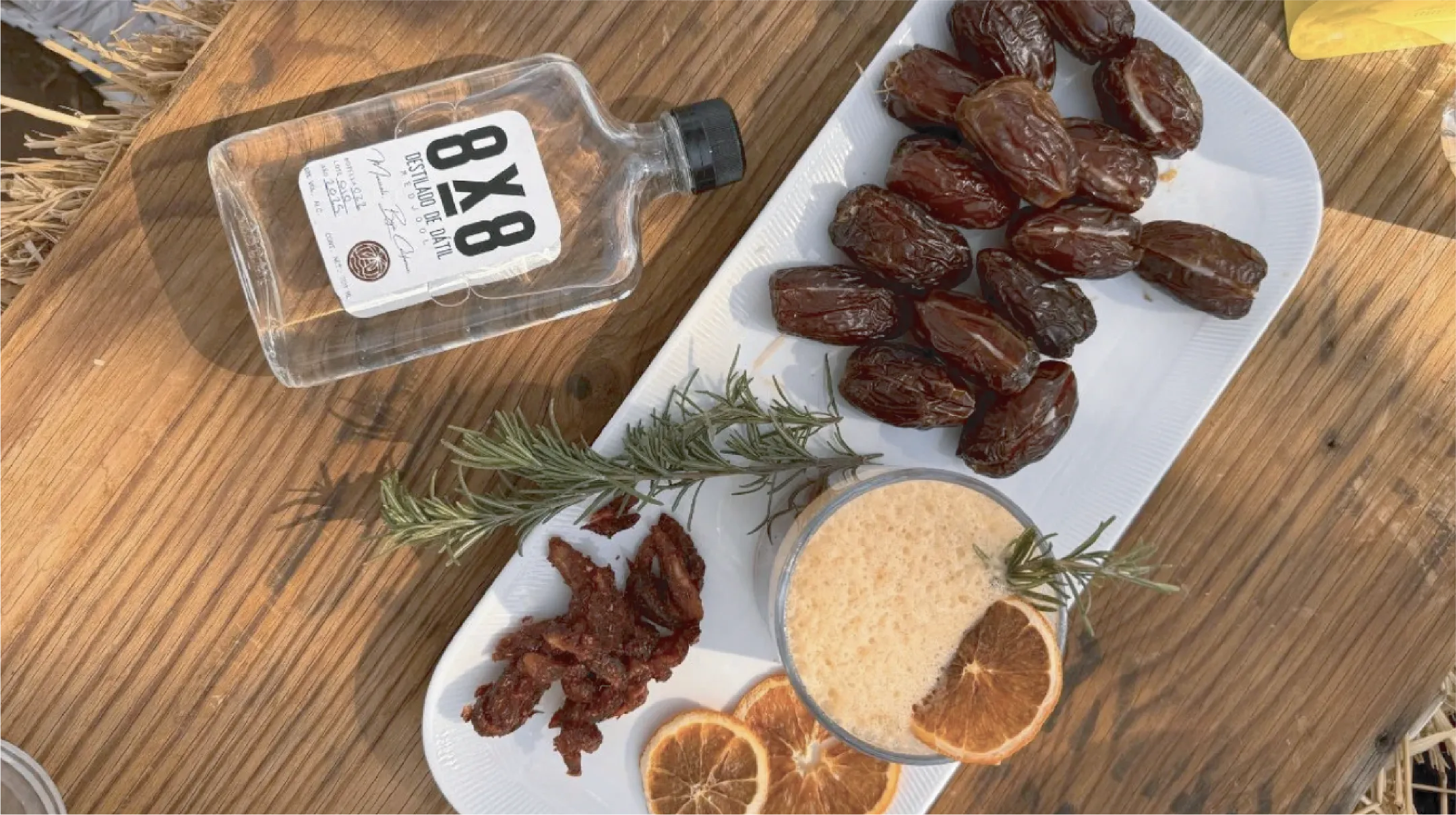 Una chica con un sombrero azul sosteniendo una canasta con vegetales, en un campo de flores con un cielo azul, viendo hacia una montaña lejana. Ruta de las flores