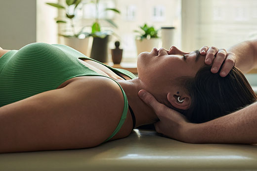 A young woman laying on her back receiving care from her chiropractor 