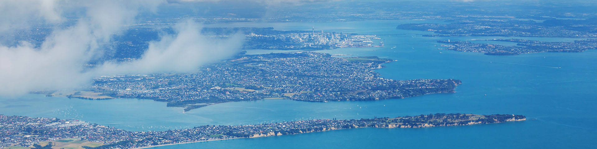 an aerial shot of Auckland in the distance with the Waitematā harbour in view