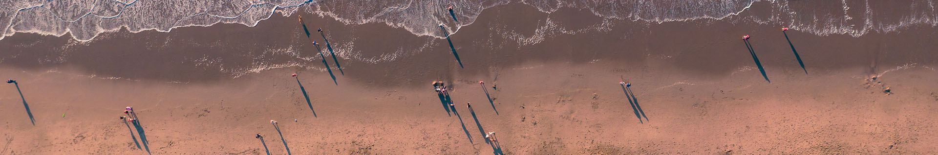 Top down aerial view of people on a beach with waves breaking on the shore