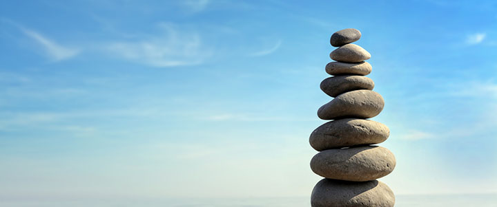 Rocks balancing on one another with a blue sky in the background
