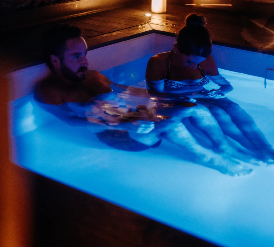 Couple sitting in a cold plunge pool using Wim Hof method for breathwork and cold exposure therapy at Aetherhaus relaxation retreat.