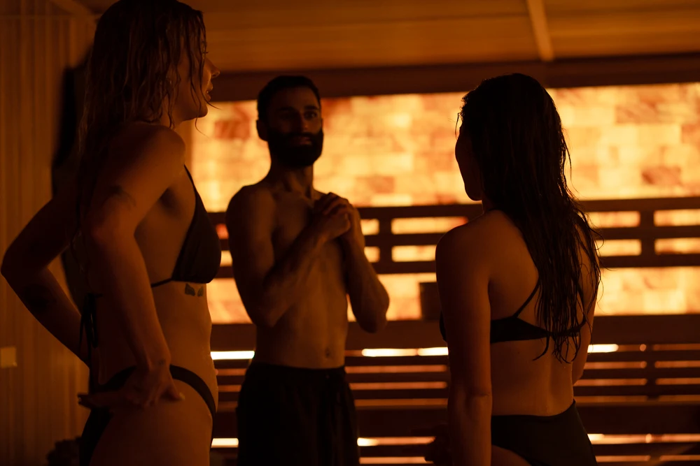 Three guests enjoying a sauna experience at Aetherhaus Vancouver, standing in a glowing Himalayan salt wall sauna designed for stillness and relaxation.