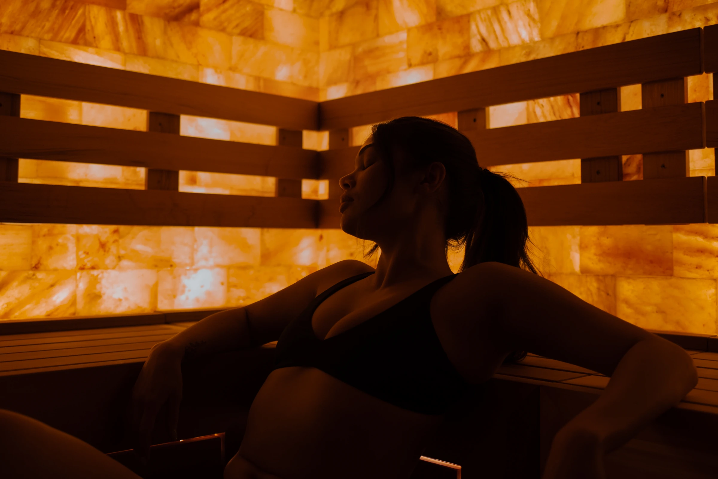 Guest resting mindfully during sauna experience inside Himalayan salt sauna at AetherHaus Vancouver.