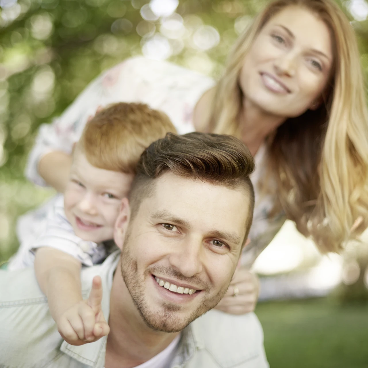Lachende Familie, Vater mit Sohn im Fokus, die Mutter dahinter