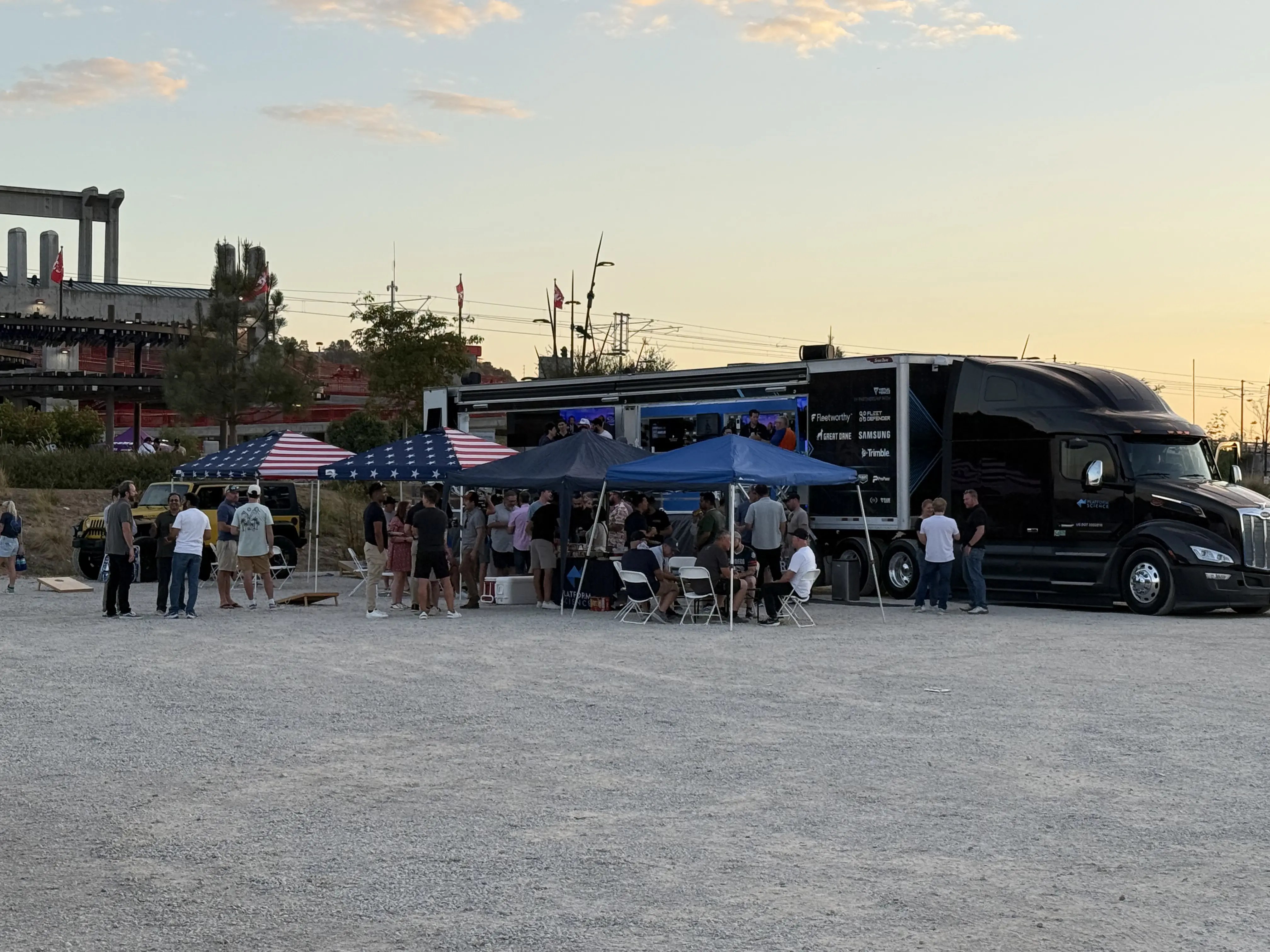 PlatScientists and partners gathered under tents beside the Connected Vehicle Lab truck at sunset