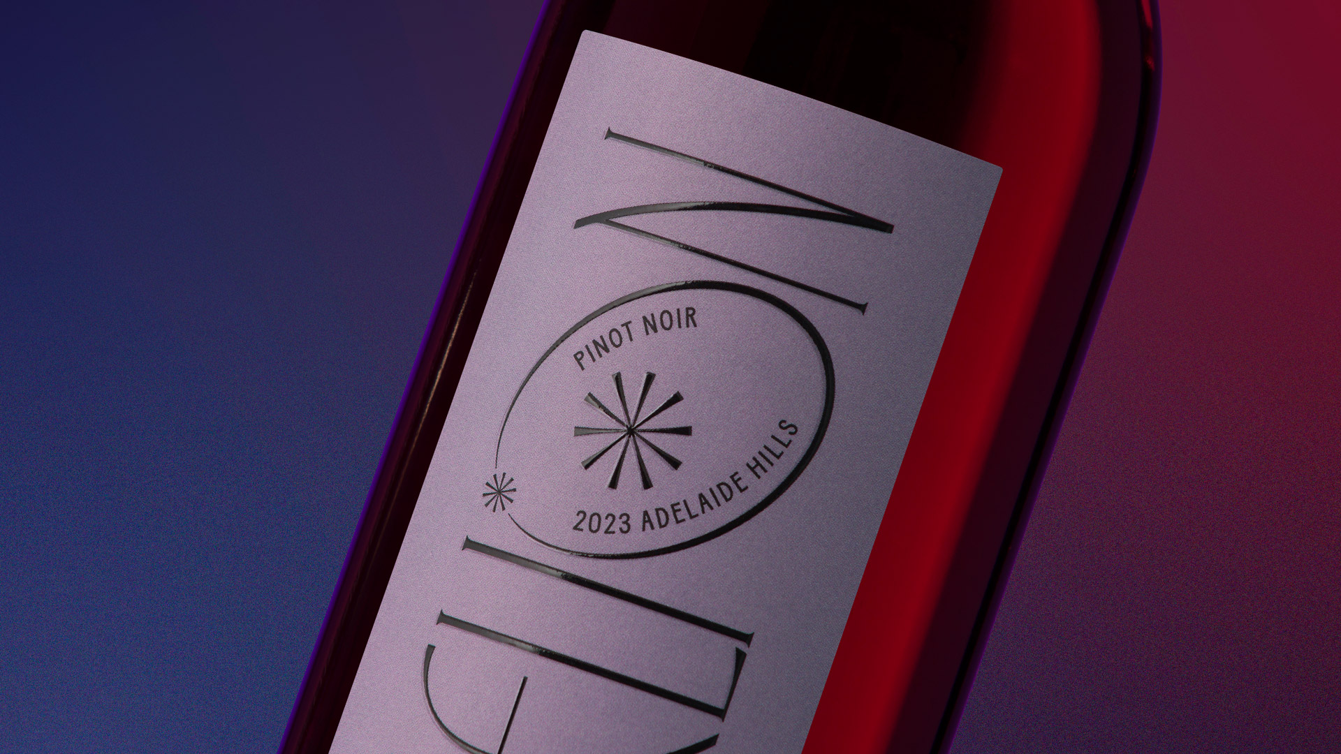 Close-up of wine label with vibrant pink and purple lighting.