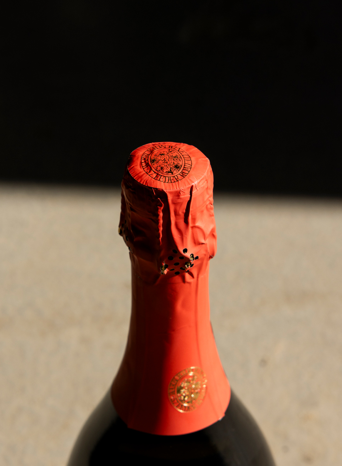 Close-up of red wine bottle with wax-sealed top.
