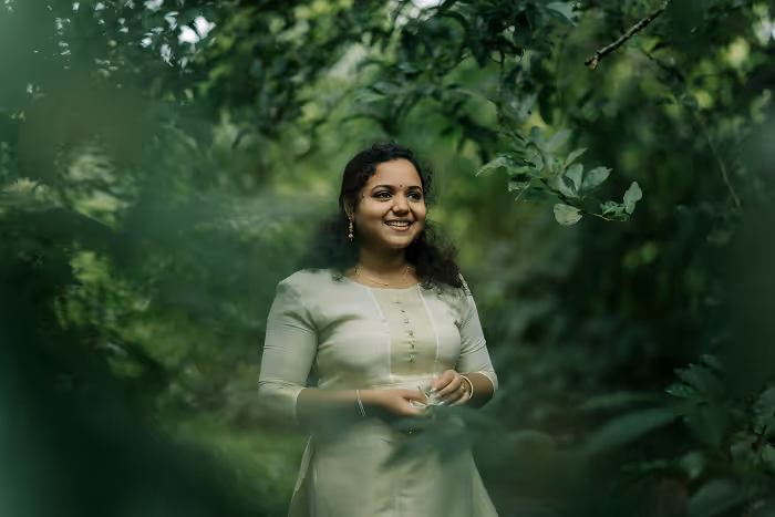 A woman in a green dress standing in a forest.