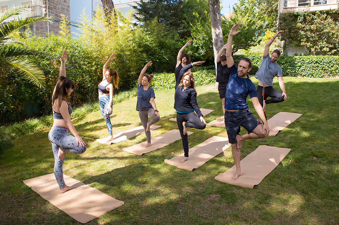 A group of people doing yoga outside in the grass.