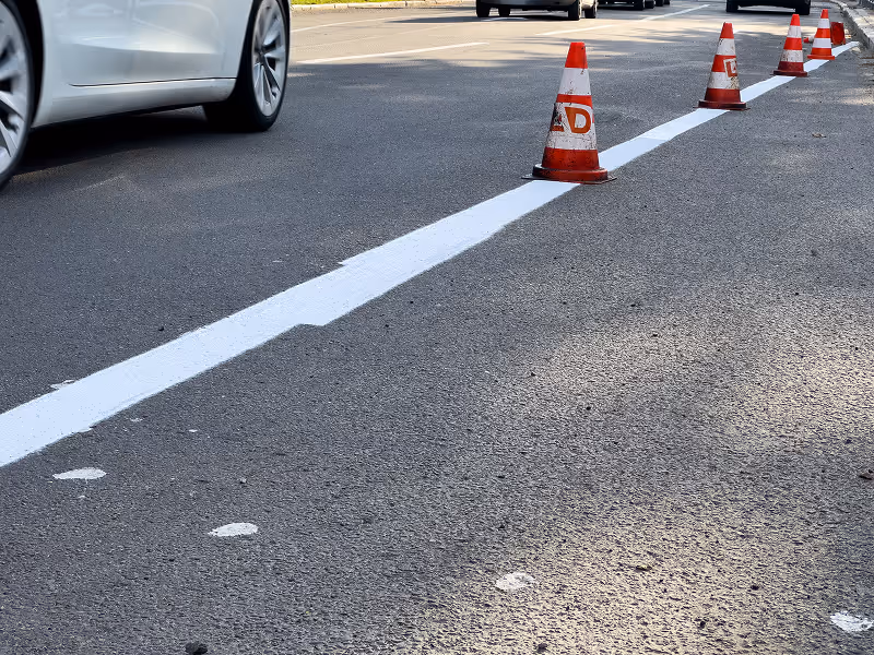 A car driving down a street next to traffic cones.