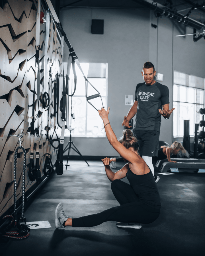 Personal trainer training woman on pistol squats