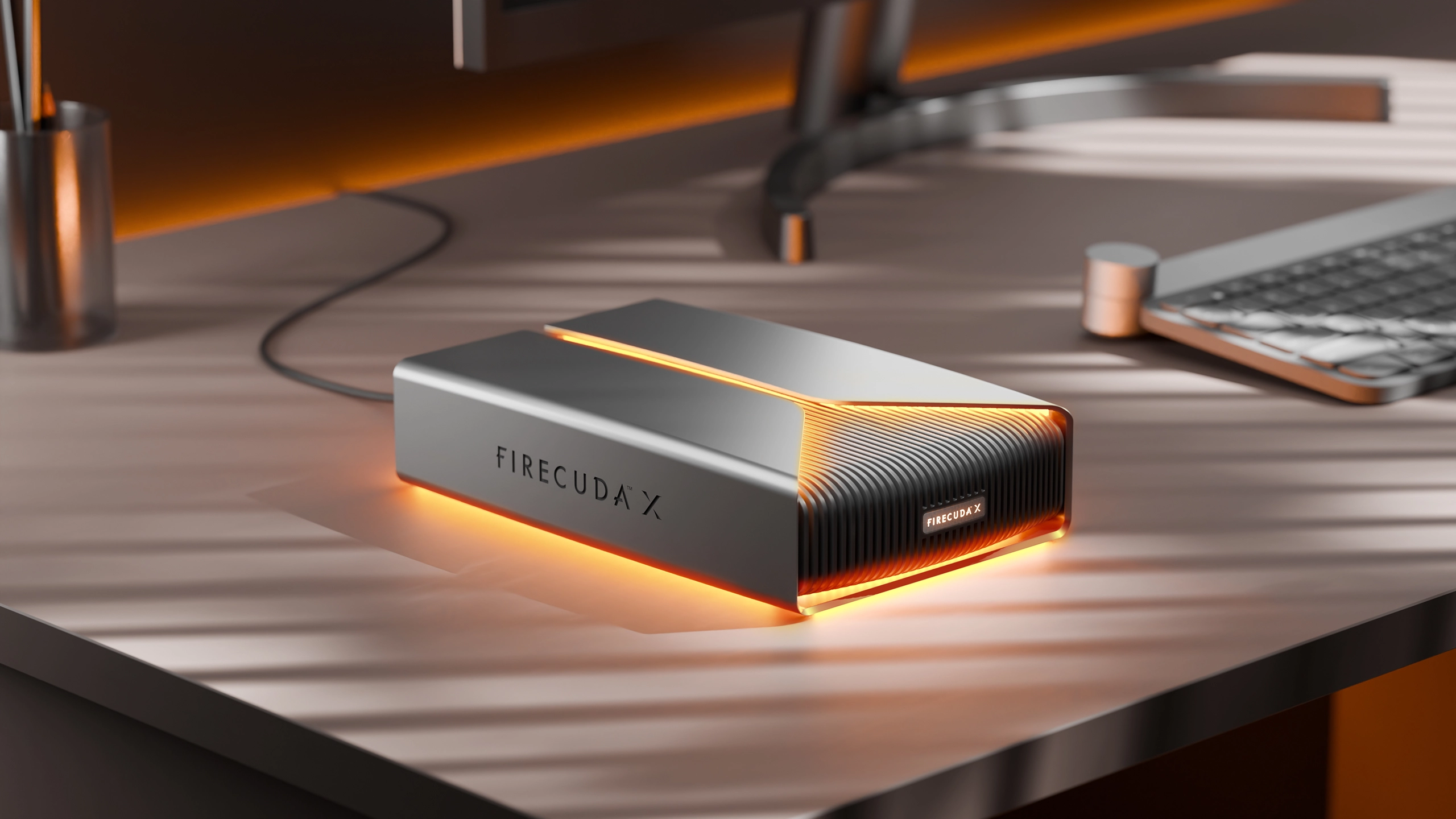 Seagate FireCuda X external hard drive with orange LED lighting on gaming desk.