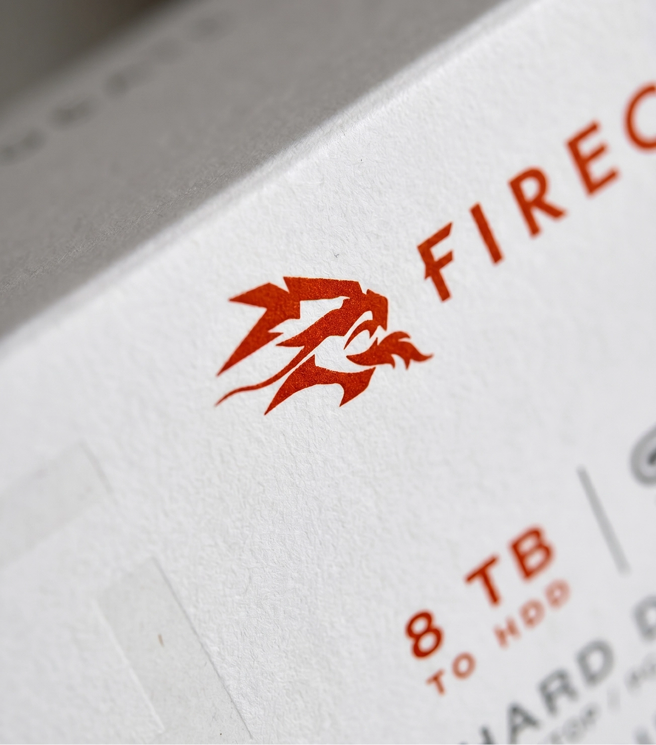 Close-up of FireCuda X logo on textured white hard drive packaging.