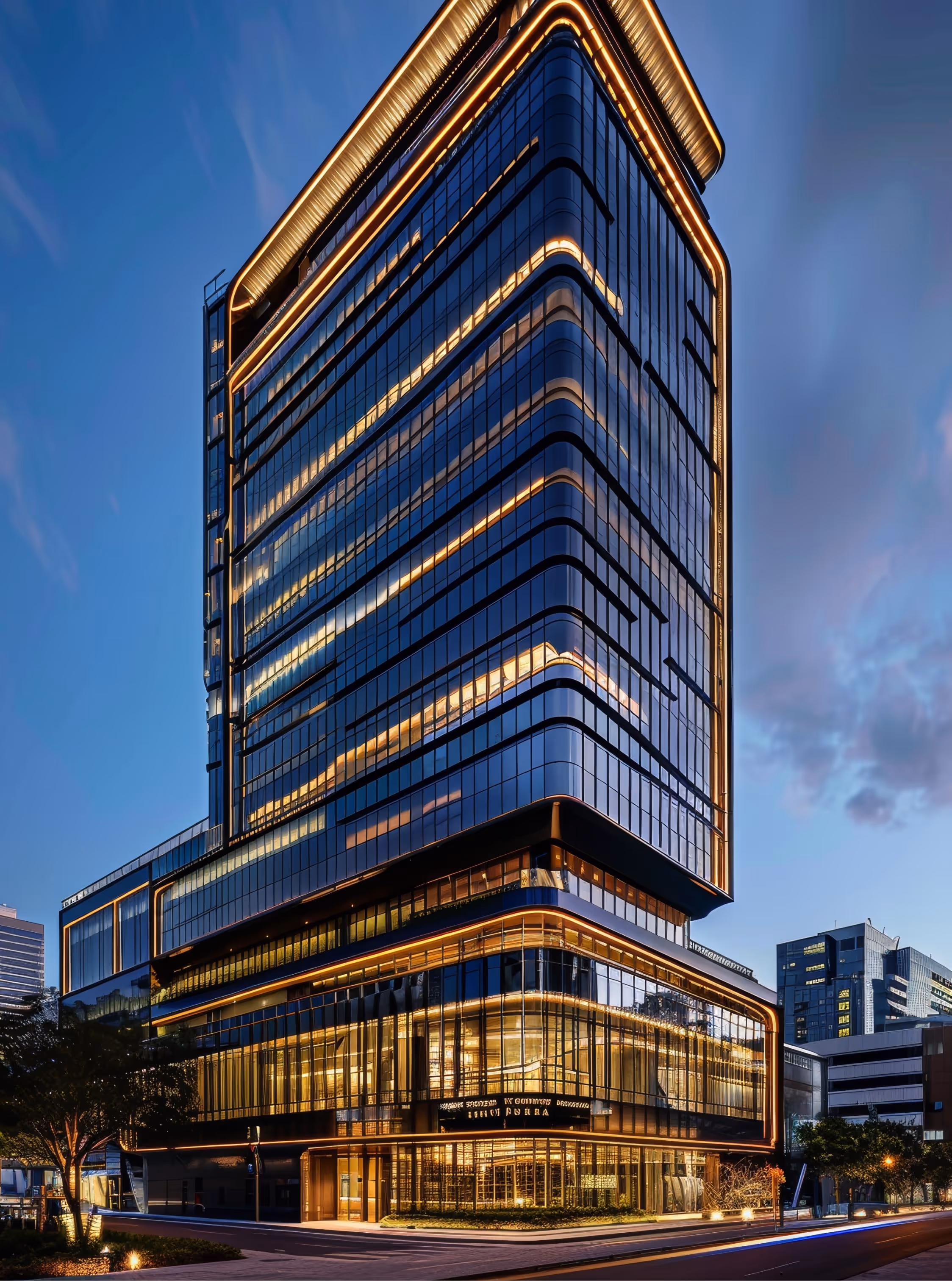 This image showcases a modern, high-rise commercial building at dusk, with its sleek glass facade reflecting the evening sky. The building is illuminated by warm, linear lights that accentuate its architectural design, creating a striking contrast against the deep blue sky. The structure features a mix of rounded and angular elements, giving it a contemporary and sophisticated appearance, likely representing a prime example of commercial real estate or investment property.
